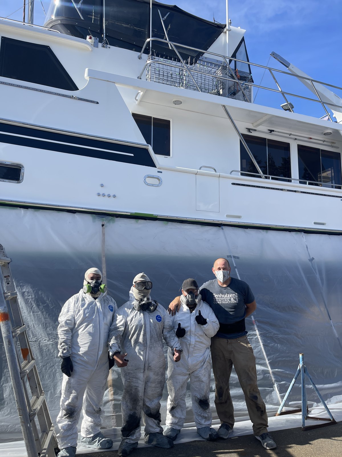 The Tenhulzen crew in front of a motor yacht with the hull tented off for bottom painting