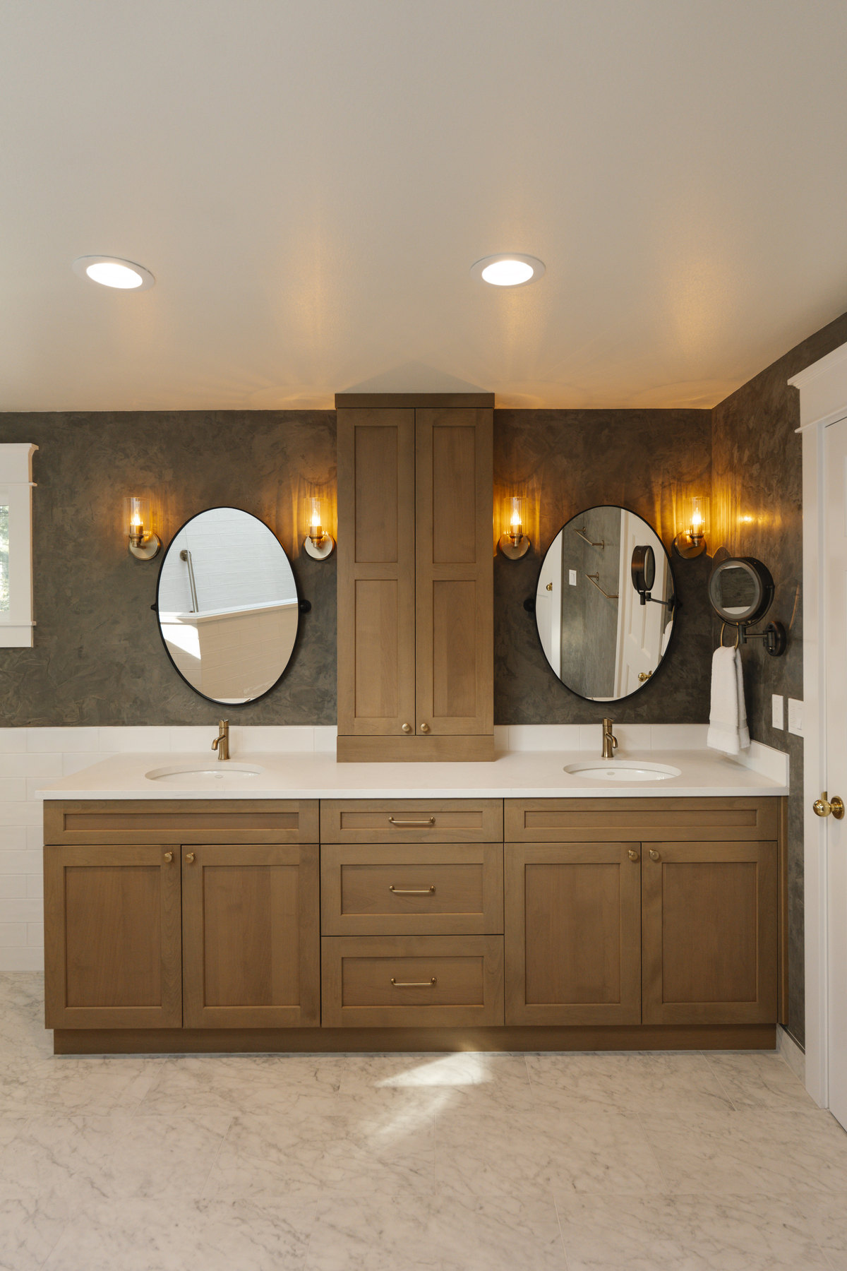 Finished primary bathroom in Mill Creek with a double vanity, twin oval mirrors and a marble tile floor